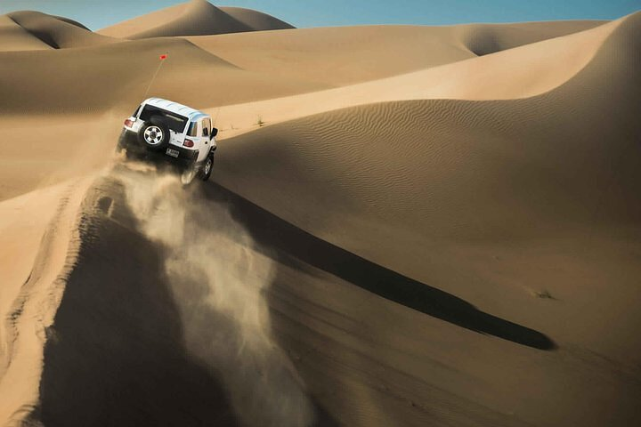 Experience the excitement of jeep off-road driving over the majestic red dunes with opportunities for sandboarding and capturing unforgettable moments in the stunning Dubai desert landscape.